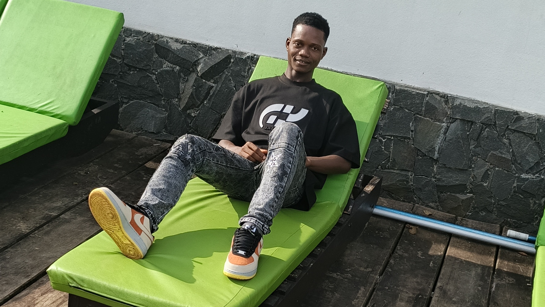 Nathan R. Watalah relaxing on lounge chair poolside during New Year's Day celebration in Maryland County, Liberia