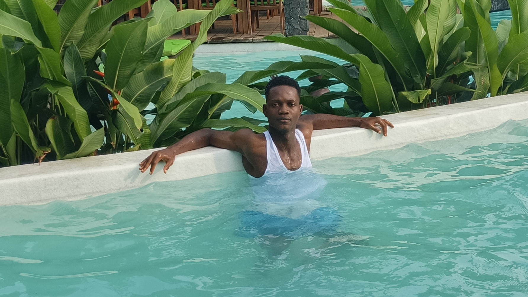 Nathan R. Watalah relaxing in tropical resort pool surrounded by banana plants during semester break in Liberia
