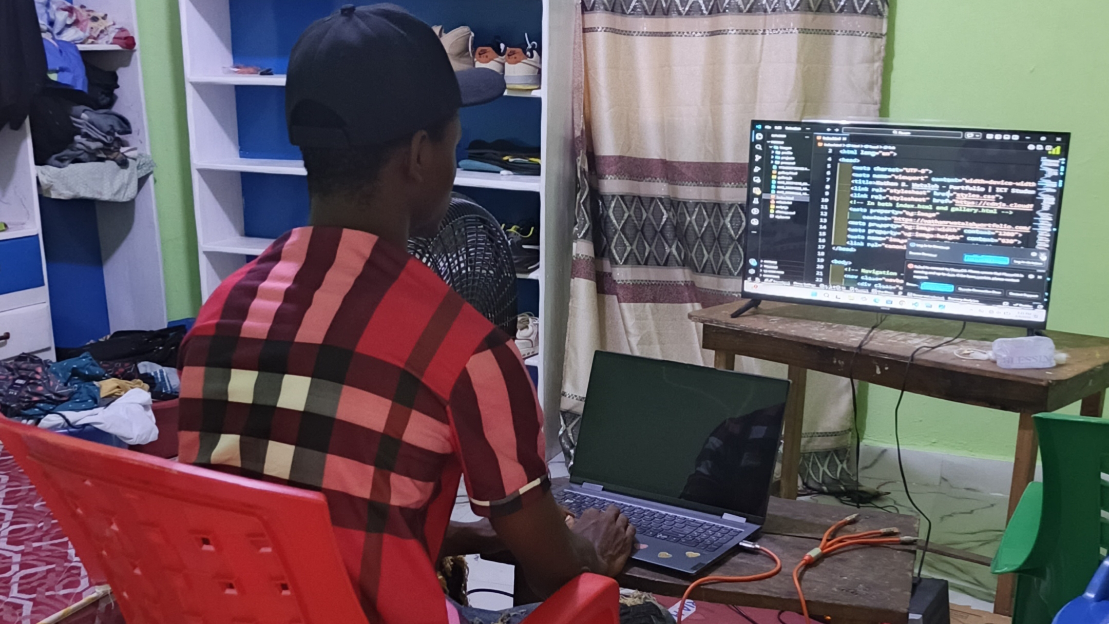 Nathan R. Watalah coding and building his portfolio website on laptop in his room in Liberia, web developer at work